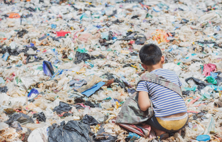 a young child squatting in a large plastic waste pile