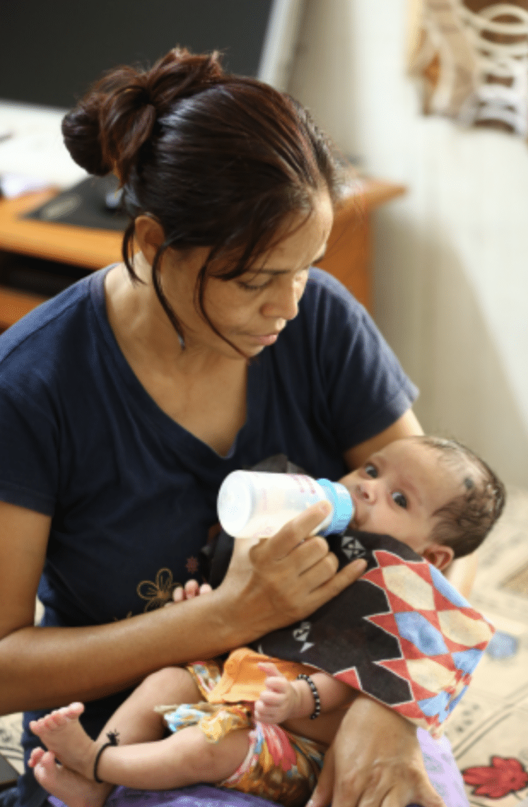 a woman bottle-feeding a baby